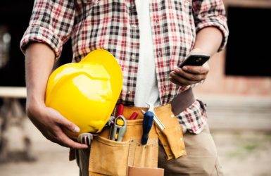 Image of a construction worker using mobile phone to create a client statement