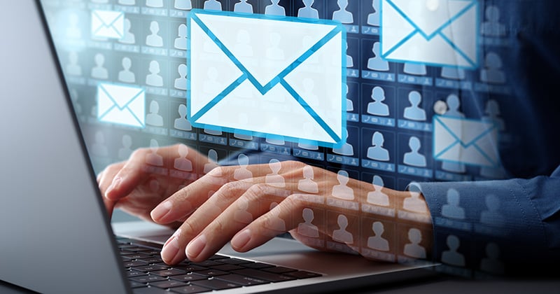 An email icon overlaid on an image of hands at a laptop.