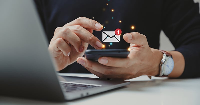 Email icon overlaid on hands holding a smartphone.