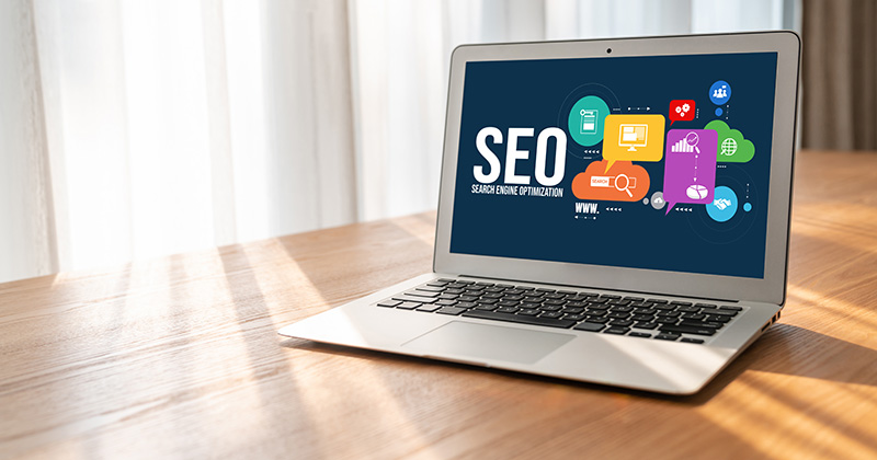 A laptop displaying a color set of icons with the word SEO in the middle of them.
