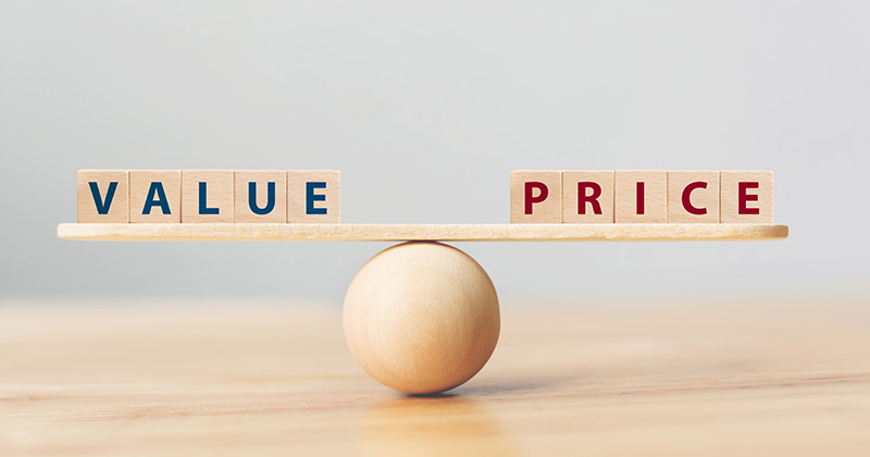 Wood-blocks-spelling-_value_-and-_price_-are-balanced-on-a-wooden-plank-on-top-of-a-wooden-ball.