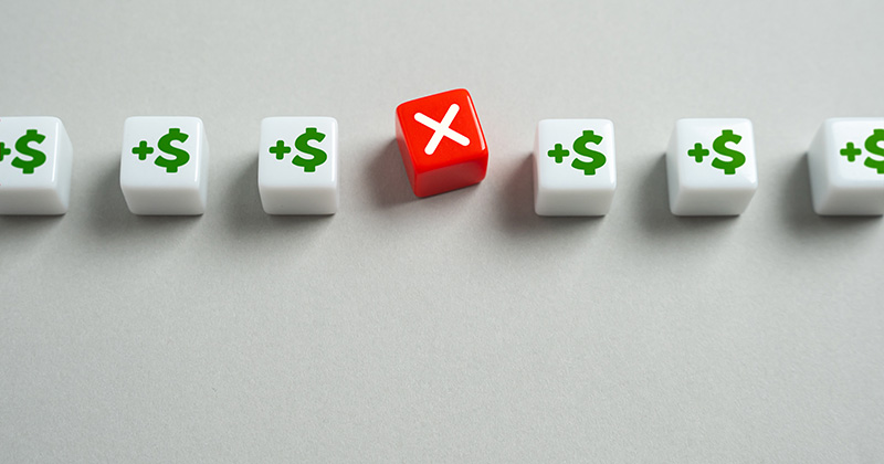 A-row-of-plastic-cubes-with-dollar-sign-icons-except-the-middle-cube-is-red-and-has-a-large-_X_-on-it.