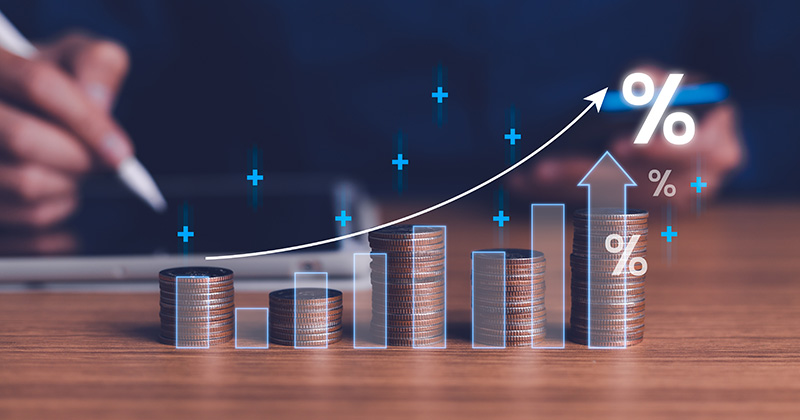 Five-stacks-of-quarters-of-various-heights-on-a-desk-with-arrows-and-percentage-symbols-overlaid-on-top-of-them.